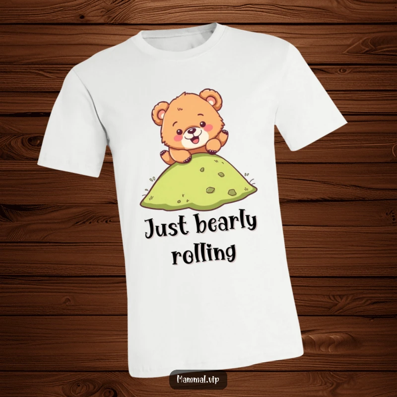 Funny t-shirt featuring a cute bear cub character playfully tumbling head over heels down a green hill, radiating happiness.